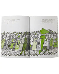 Illustrated book open to a page with a green crocodile character among people in a store.